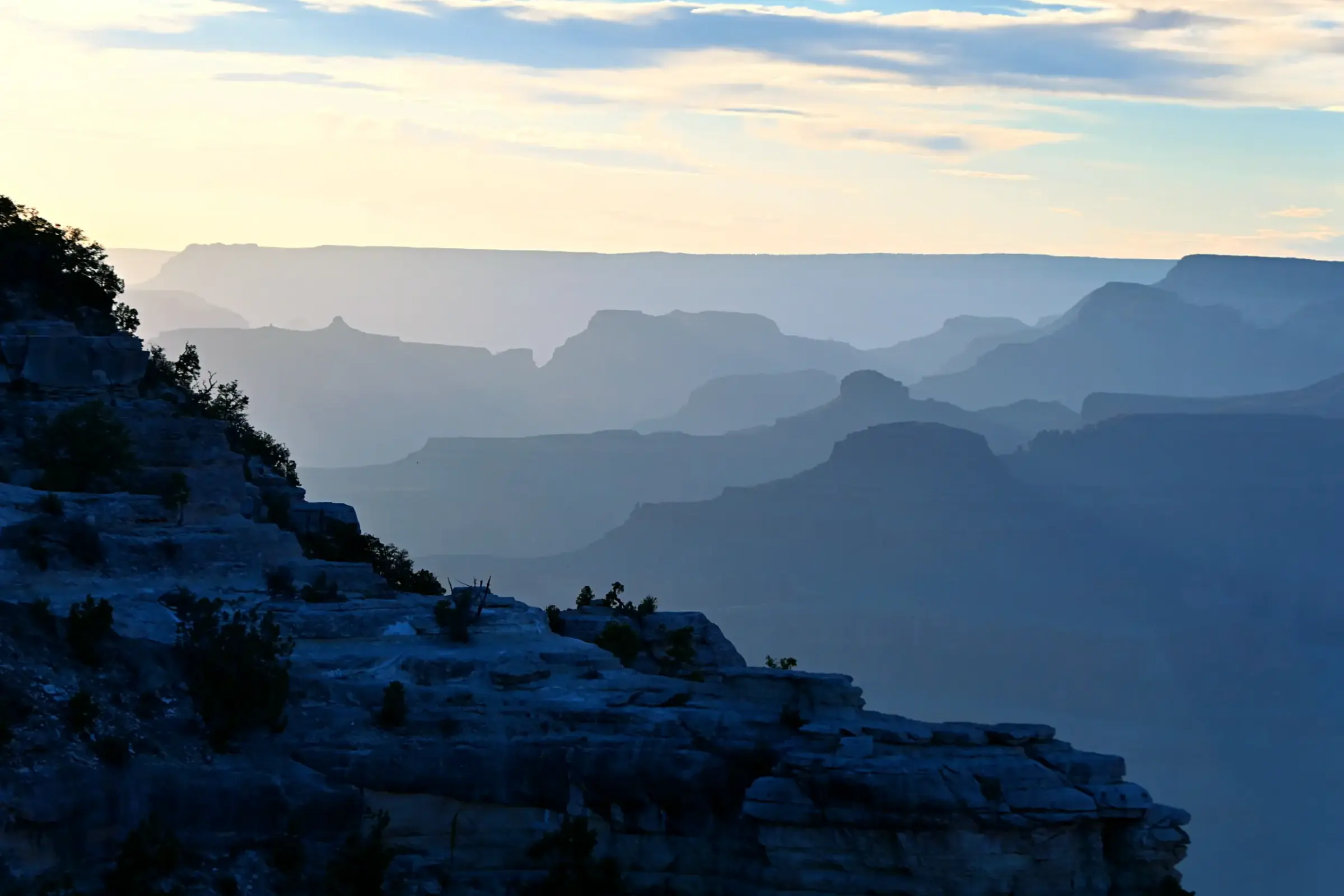 The canyon fading into blue silhouettes beneath a soft afternoon sky