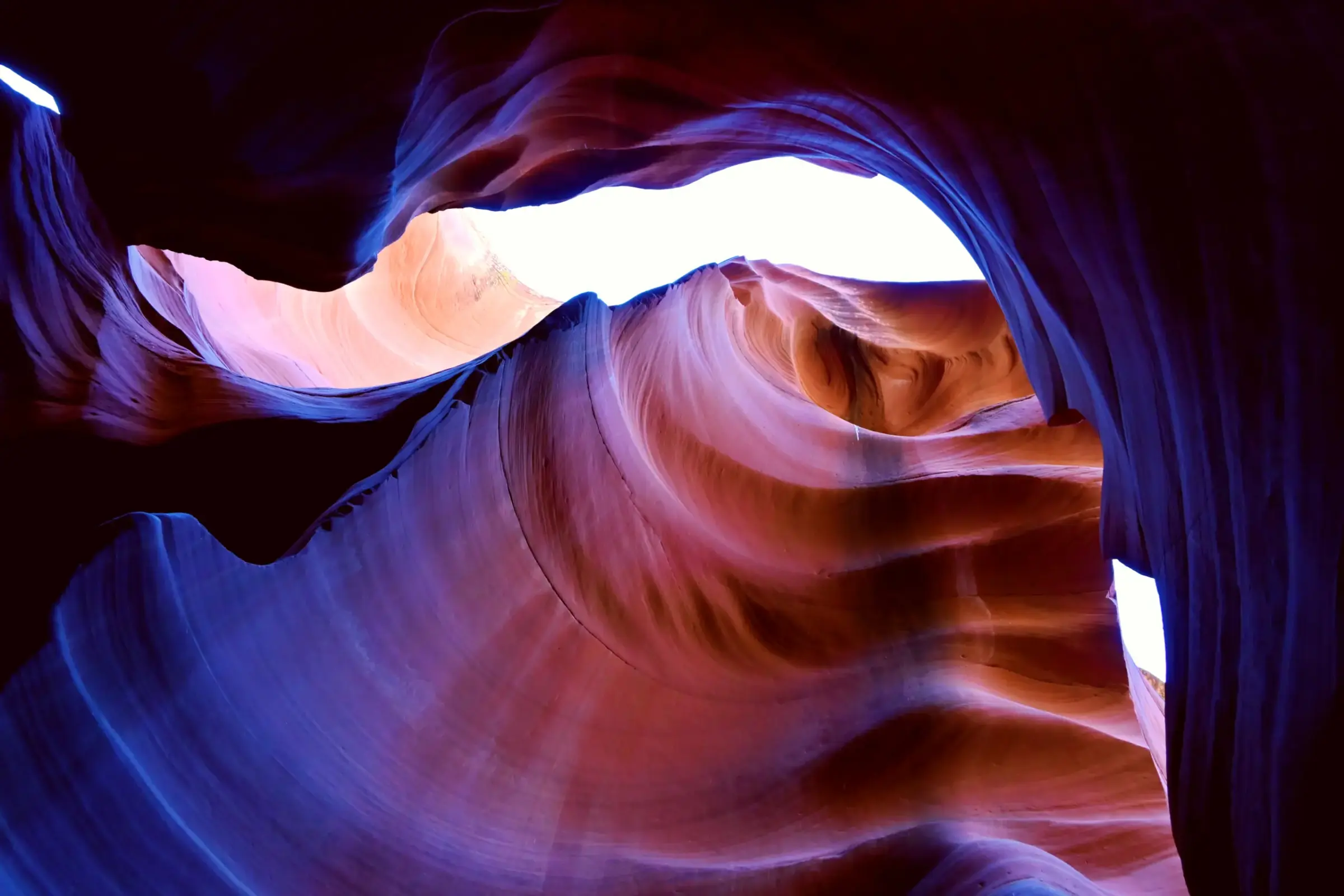 Sculpted sandstone glowing in violet and crimson inside Antelope Canyon