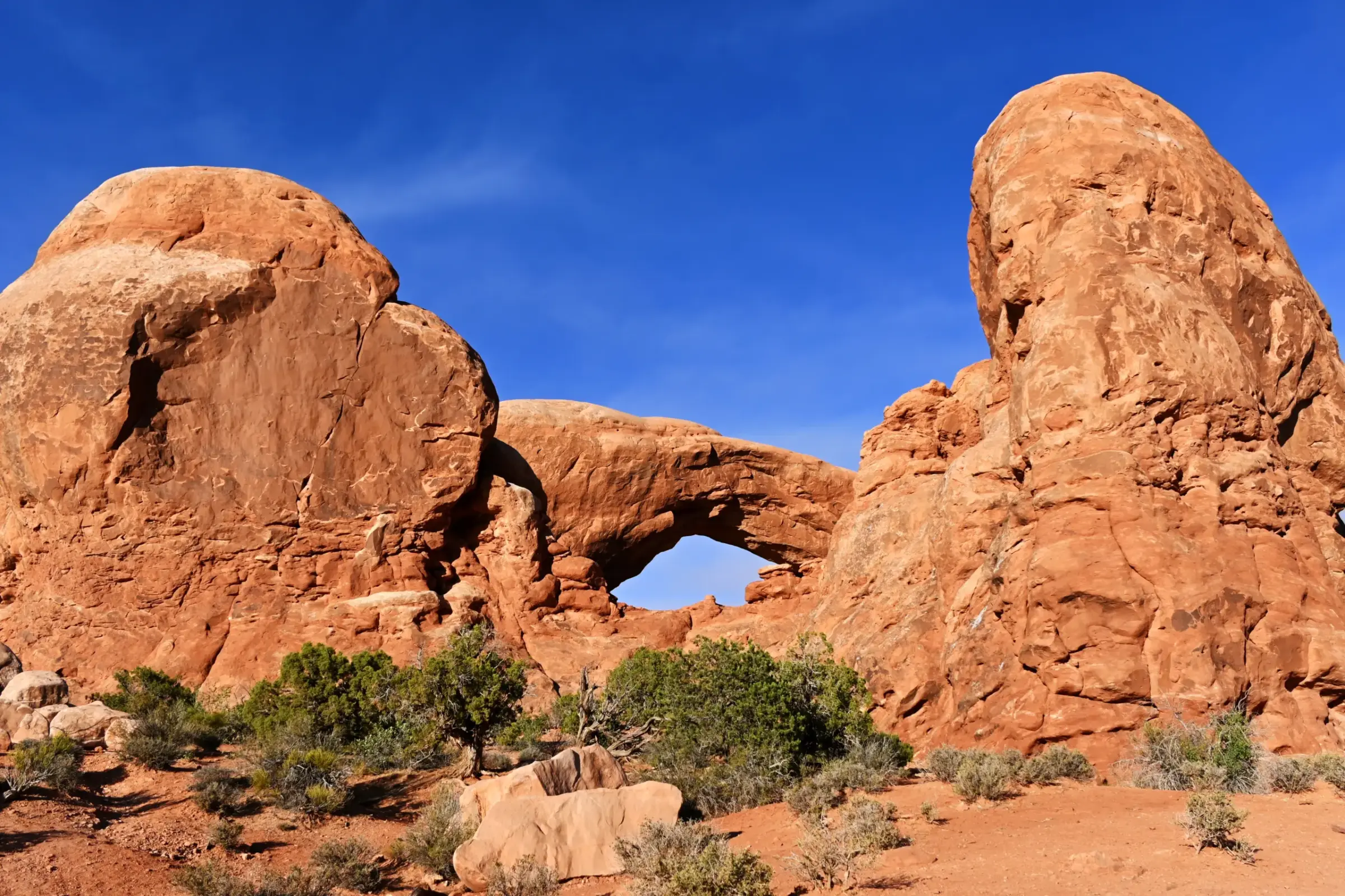 A natural sandstone arch framed by massive red-rock formations in Arches National Park