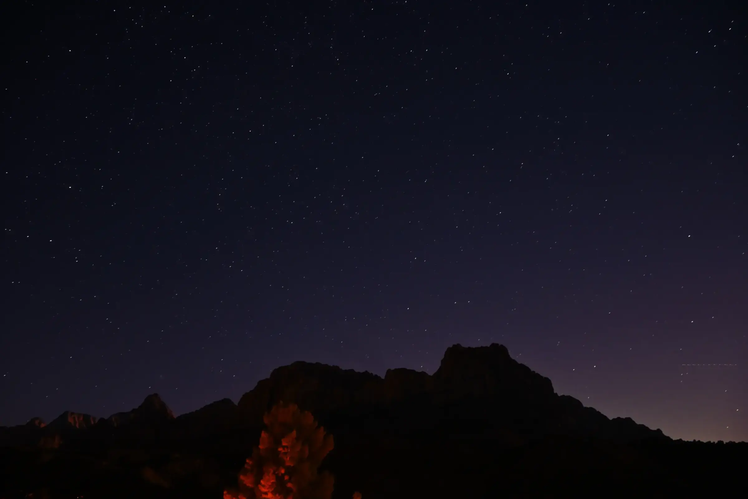 A star-filled night sky above the dark mountain silhouettes of Zion, from my stay